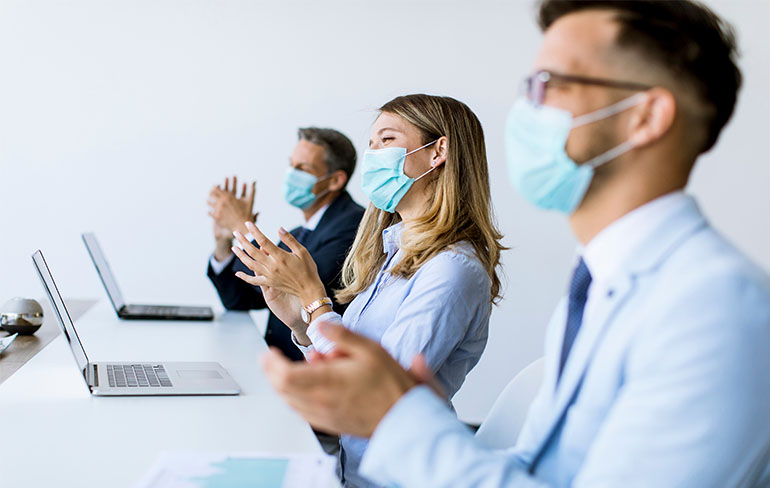 Group of business people clapping wearing masks