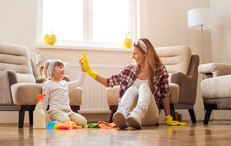 Mother and toddler daughter high-fiving each other while cleaning