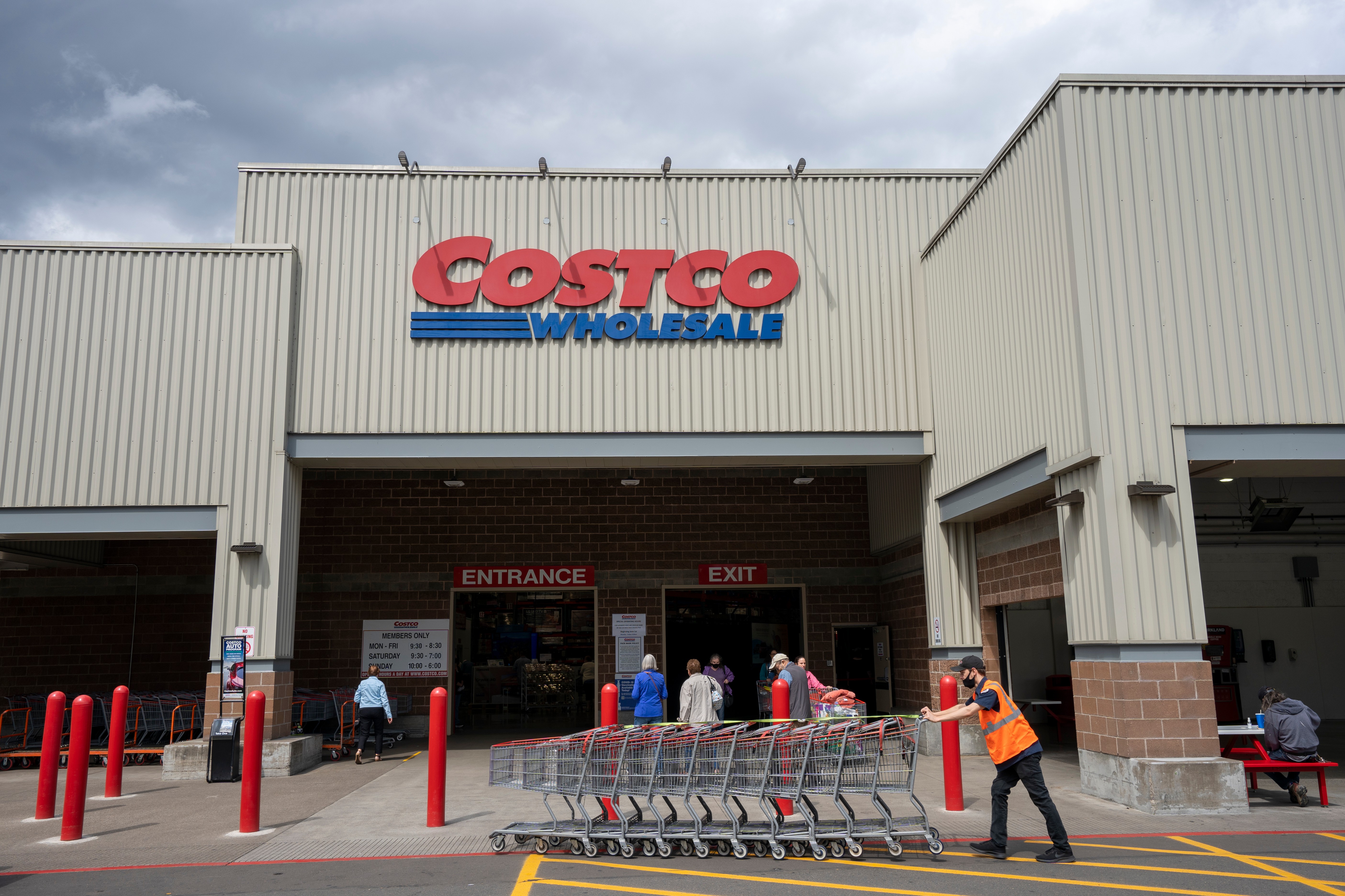 costco employee pushing carts in front of the store 