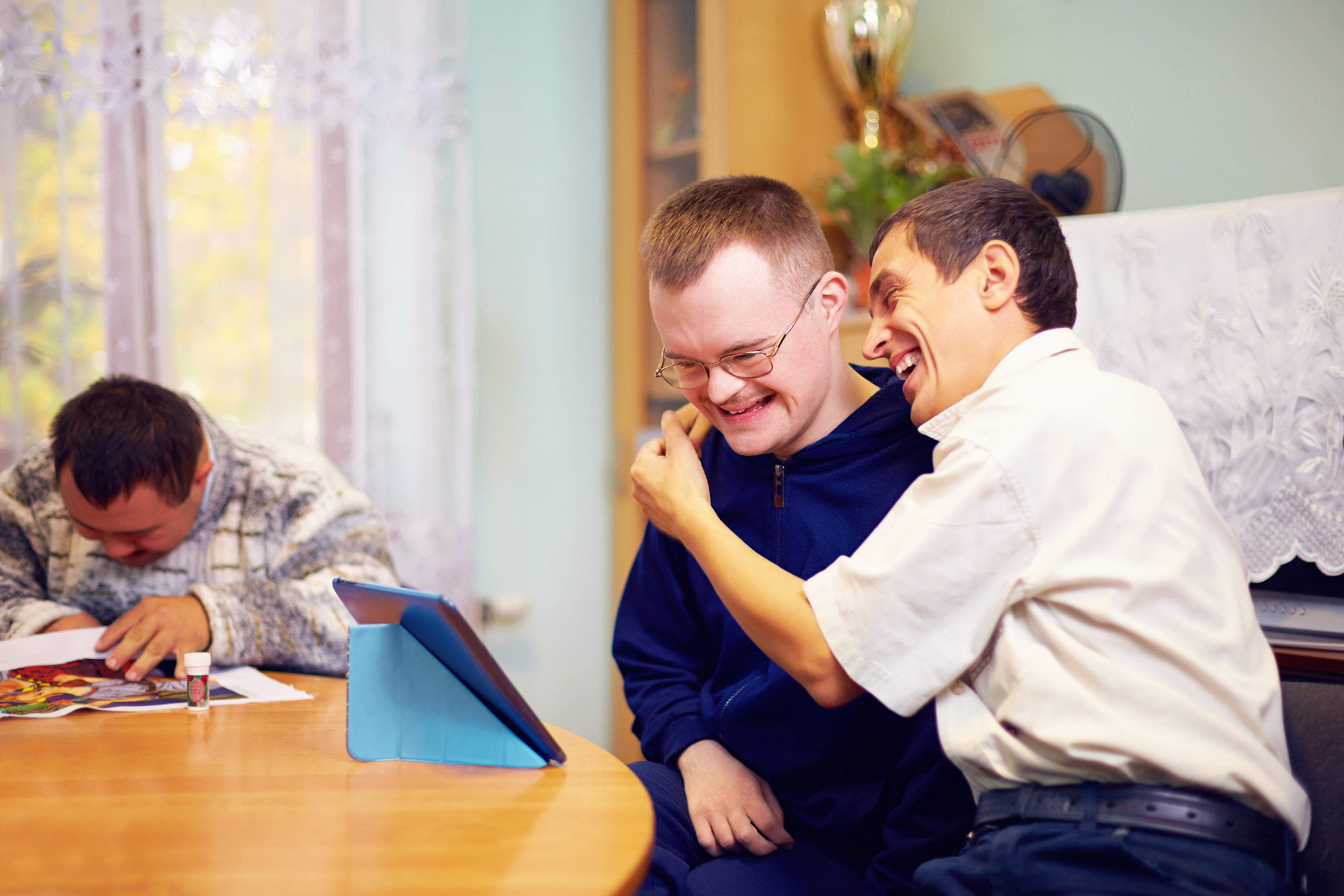 Happy friends with disability looking at tablet