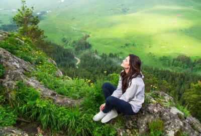 woman sitting on cliff enjoying nature