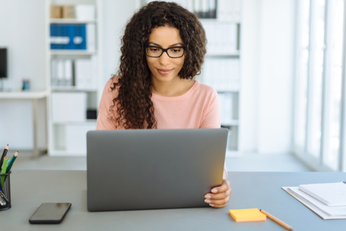 woman with glasses looking at laptop